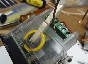 Butter the bottom of the neg. strip with epoxy and feed it down under the cell using small nose pliers. Locate it along the diagonal edge of the PC board. Then slip a balsa wedge over the top of the cell to hold things together while the epoxy sets.